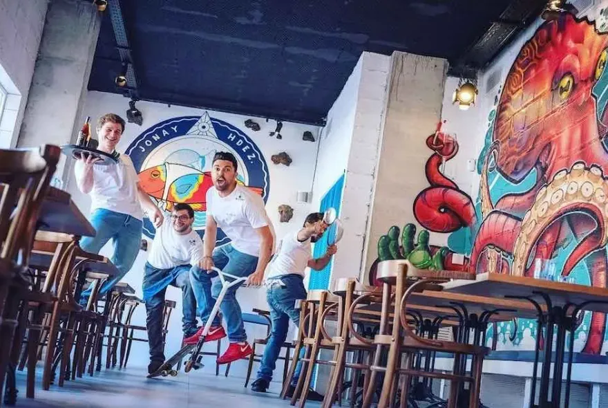 Equipo de cocina en acción dentro del restaurante Jonay Hernández, con mural artístico de pulpo y decoración moderna. La escena transmite energía, creatividad y el espíritu joven del local.