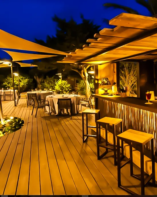 Terraza nocturna de Es Mal Pas Formentera con mesas vestidas, barra de madera y ambiente cálido