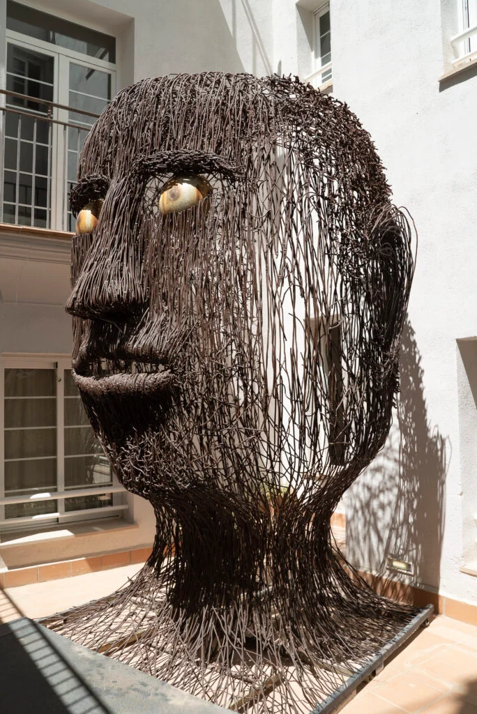 “Escultura artística de cabeza humana formada por varillas metálicas en el interior del Hotel Artmadams.”