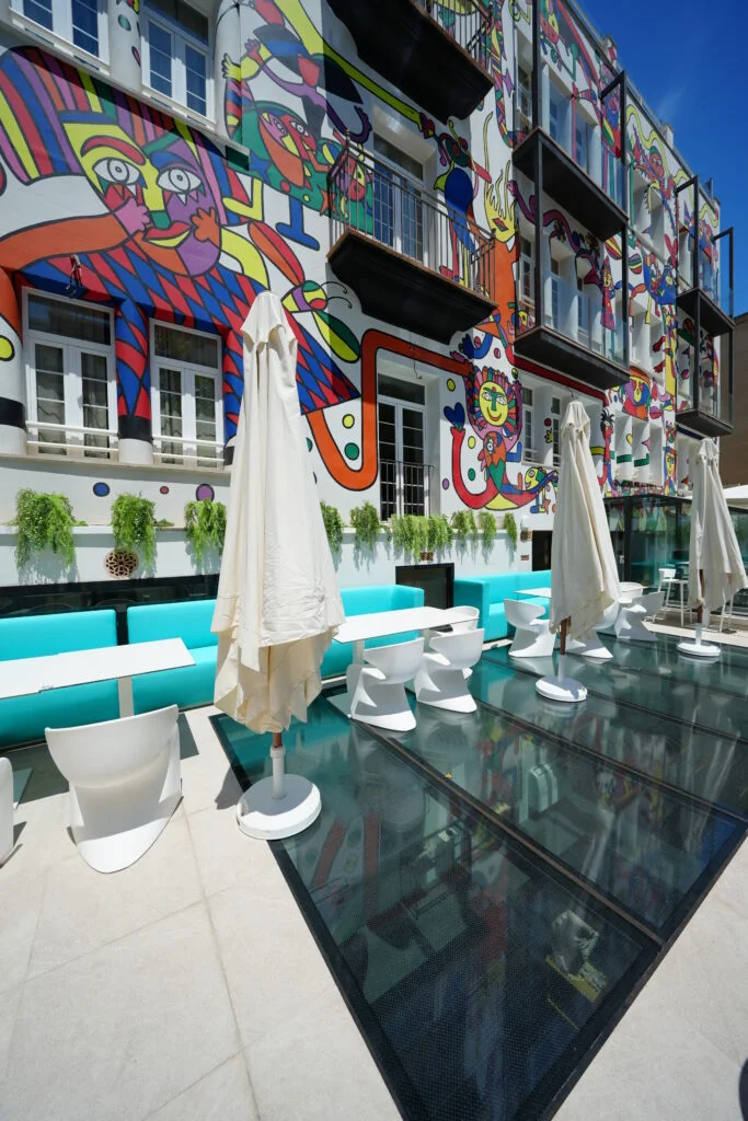 “Terraza del Hotel Artmadams frente a un mural artístico de colores vibrantes.”