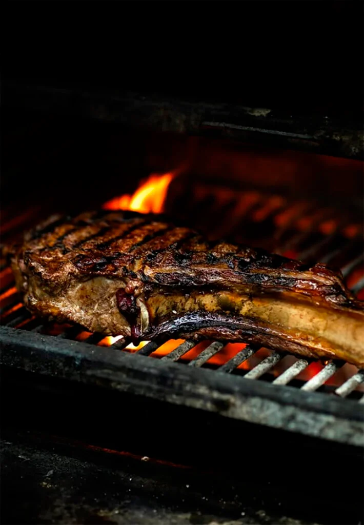 “Tomahawk a la brasa en la parrilla de La Guarida de Palma con fuego vivo.”