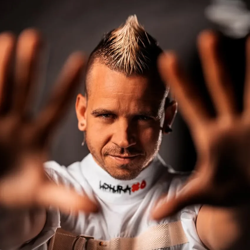 Dabiz Muñoz con mohawk rubio y chaqueta tipo camisa de fuerza, mirada intensa frente a fondo oscuro