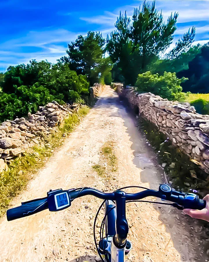 Ruta ciclista en Formentera entre muros de piedra, vegetación y cielo azul