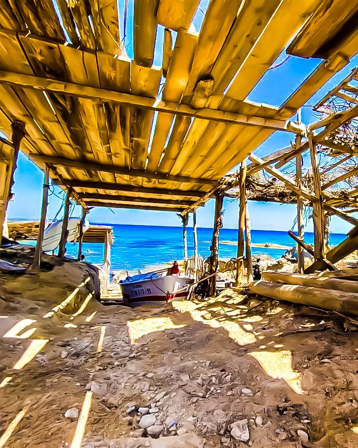 Cobertizo de madera con barca en la costa de Formentera, frente al mar turquesa